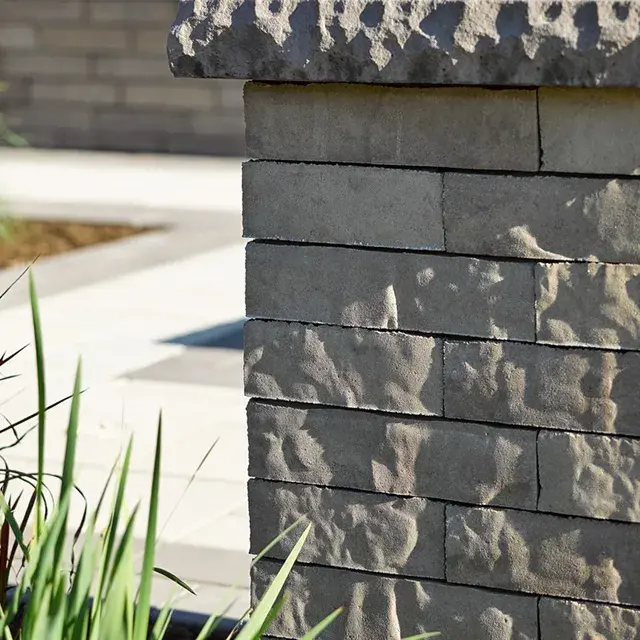 Brandon by Techo-Bloc, rustic double-sided retaining wall blocks with a dry-stacked appearance, creating a sturdy and textured boundary for outdoor spaces.