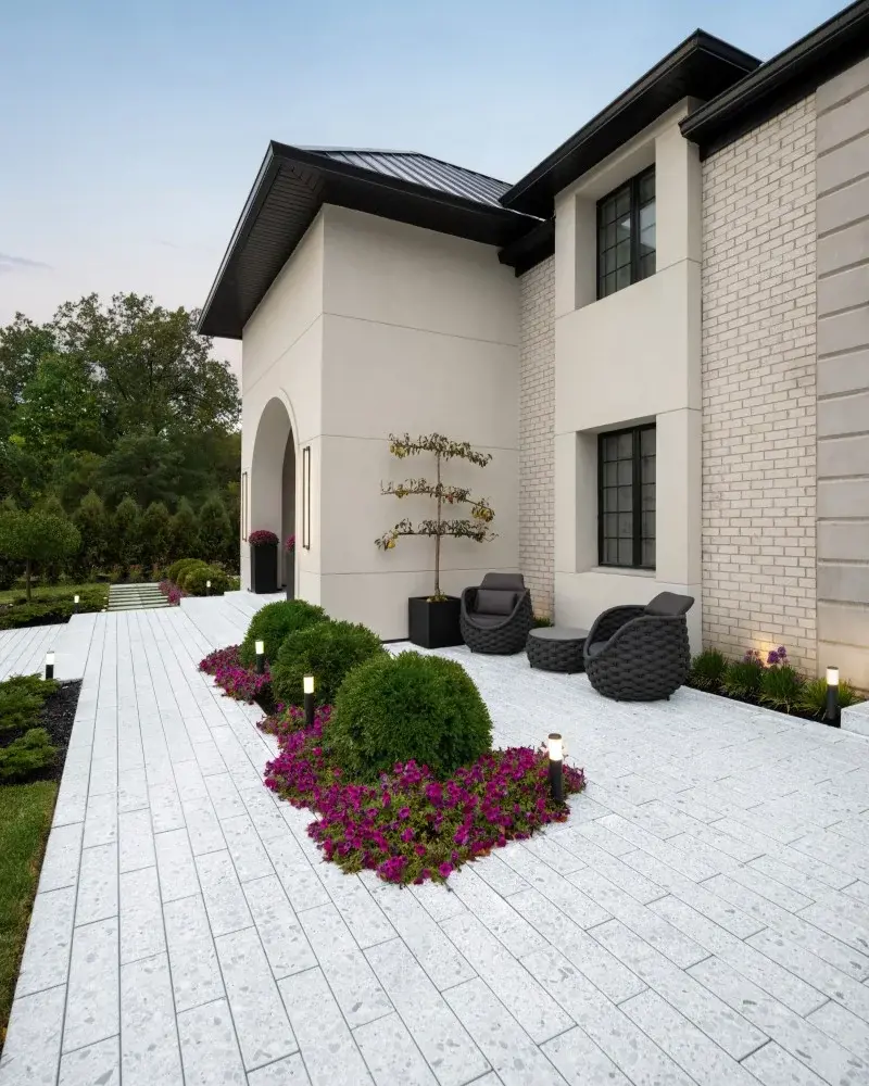 Contemporary front courtyard with Mineral White Terrazzo slabs, outdoor seating, and flowering landscape border.