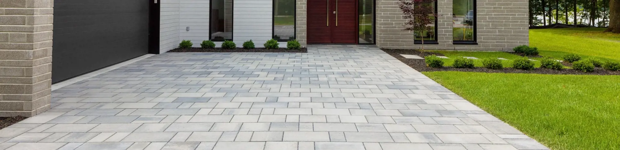 Blu 80 Smooth paver by Techo-Bloc in Greyed Nickel with smooth texture, forming a clean-lined driveway in front of a modern home.