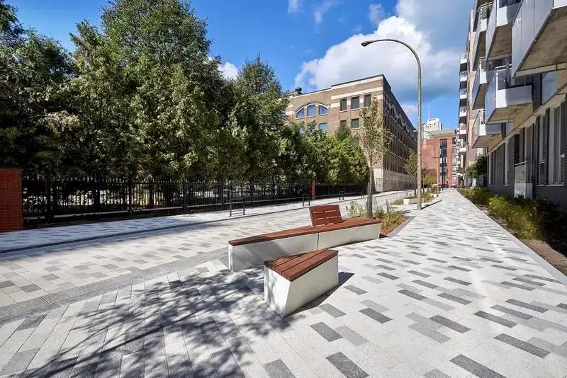 Urban park with Techo-Bloc commercial pavers in mixed grey tones, installed in a modular pattern beside benches and mature trees.