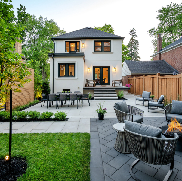 Elegant urban courtyard with light-colored flagstones, green lawn inserts, lounge chairs and privacy fence.