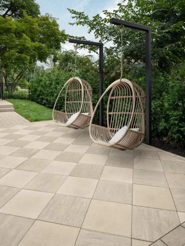 Warm neutral tones on patio with creamy stone pavers and swing chairs.