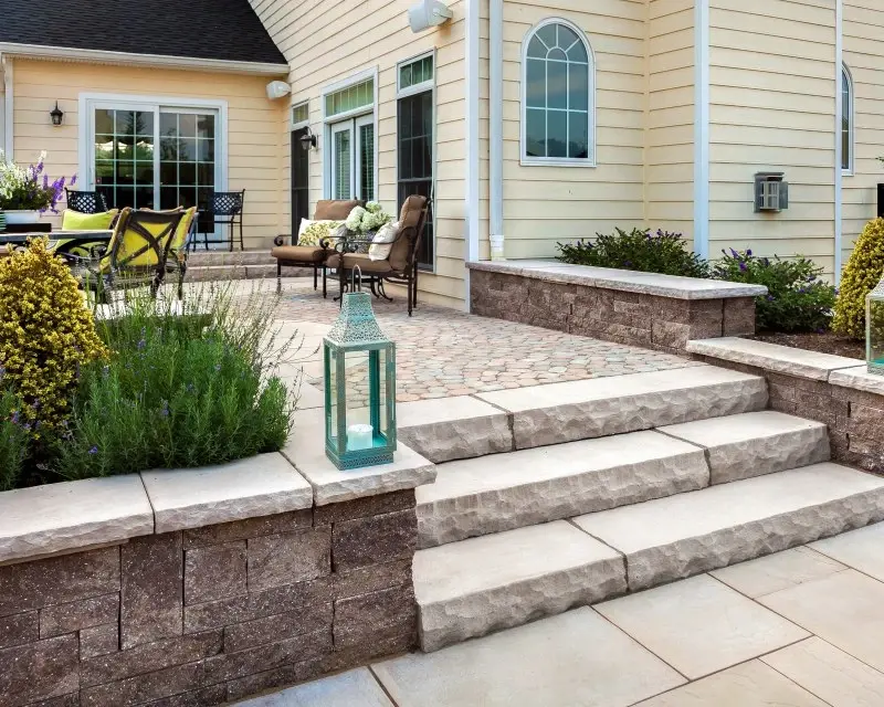 Mini-Creta garden wall in split-stone texture, framing a modern outdoor patio with seating area.
