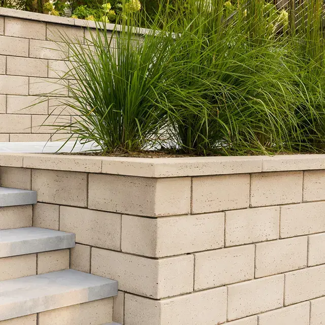 Travertina Raw by Techo-Bloc, luxurious travertine wall blocks forming a retaining wall with a smooth, natural finish, ideal for landscaping and outdoor features.