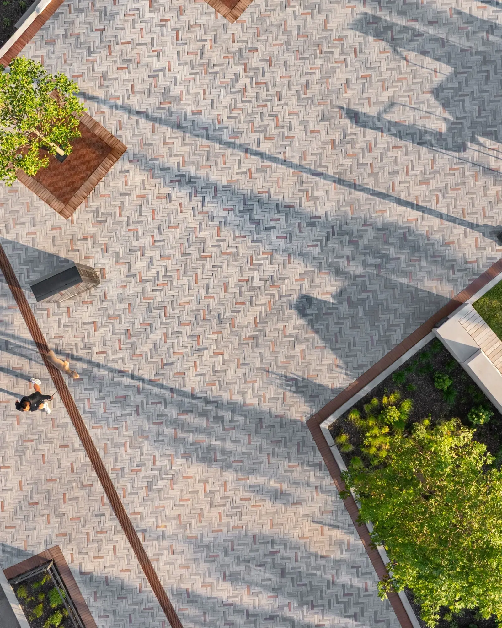 Vue aérienne des pavés Westmount HD² Smooth en motif chevrons doubles entrelacés, intégrés avec des espaces verts et des jardinières.
