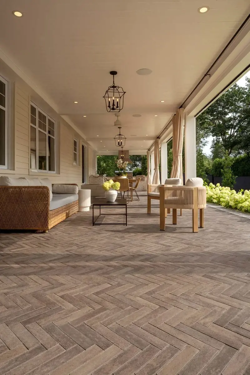 Resort-style covered patio with warm-toned Techo-Bloc slabs, comfortable dining area, and seamless indoor-outdoor flow.