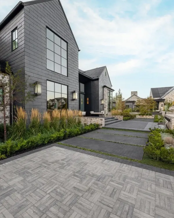 Entrée résidentielle en pavés de béton emboîtables à motif chevrons devant une maison moderne