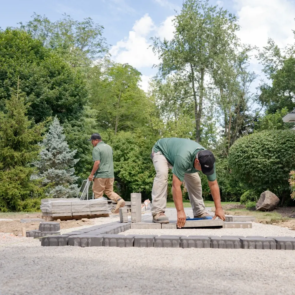 Entrepreneurs installant des pavés de béton emboîtables pour un patio et un aménagement extérieur