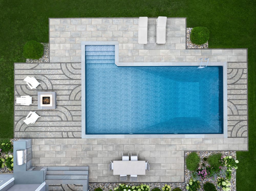 Aerial view of a linear pattern made with dark grey pavers leading up to the entrance of a pool.