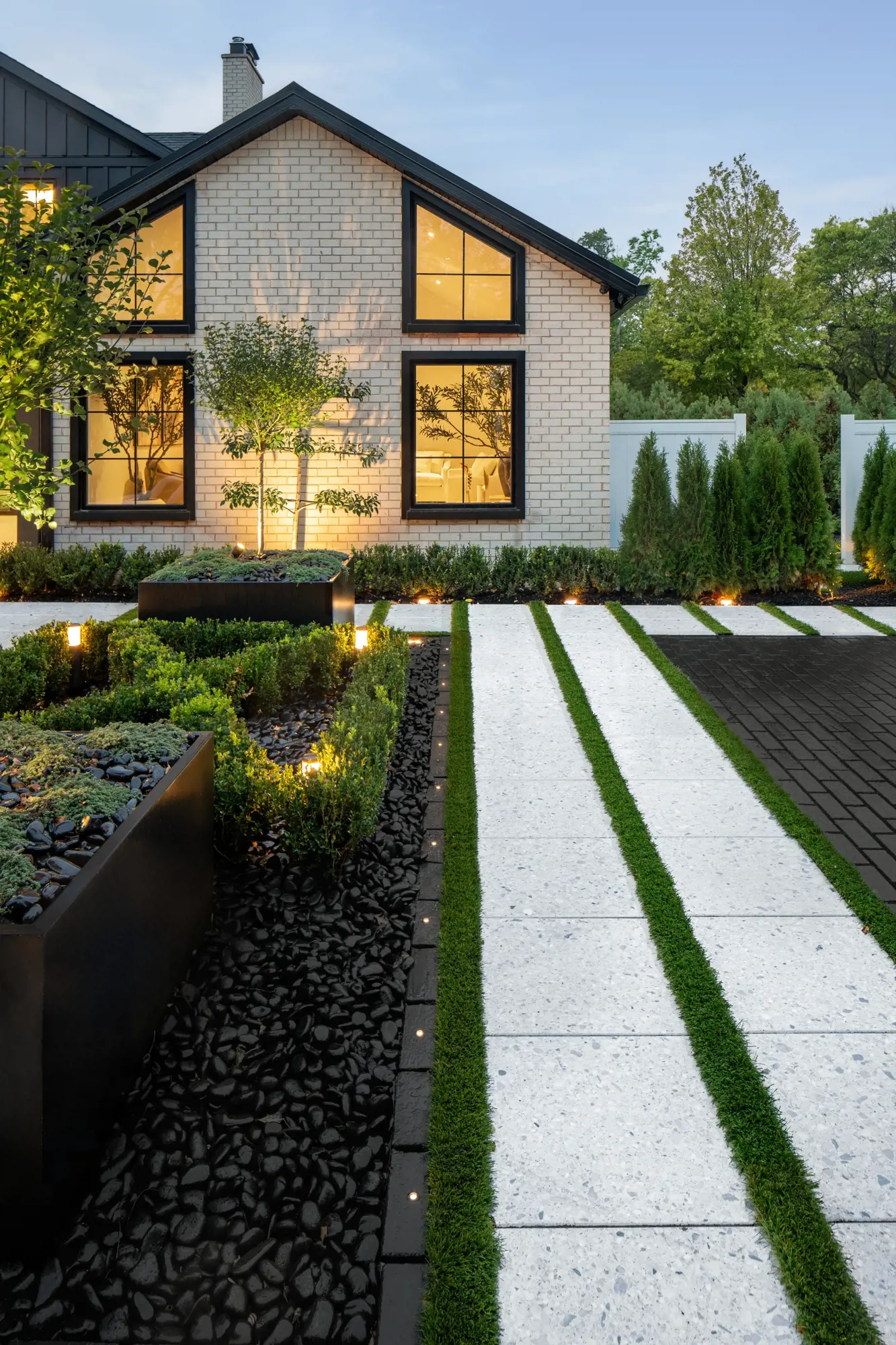 Maison au crépuscule avec deux allées en Terrazzo et une plate-bande de galets