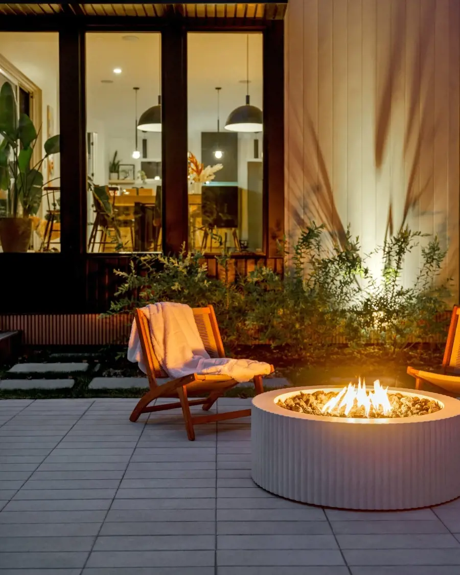 Outdoor lounge featuring a Sculptura fire pit with soft sculptural curves, serving as a refined focal point within a contemporary patio setting.