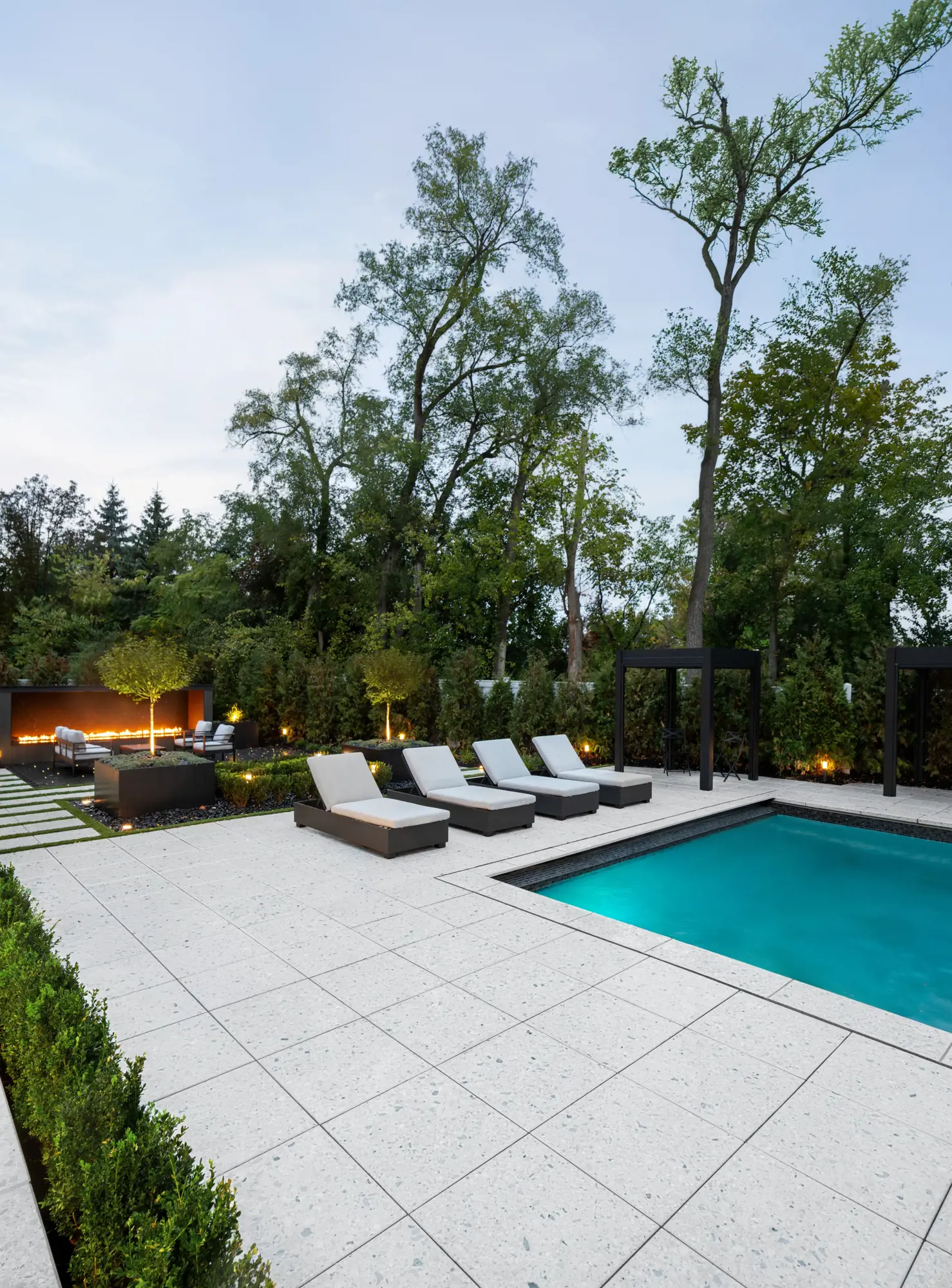 Chaises longues au bord d'une terrasse de piscine en Terrazzo entourée d'arbres
