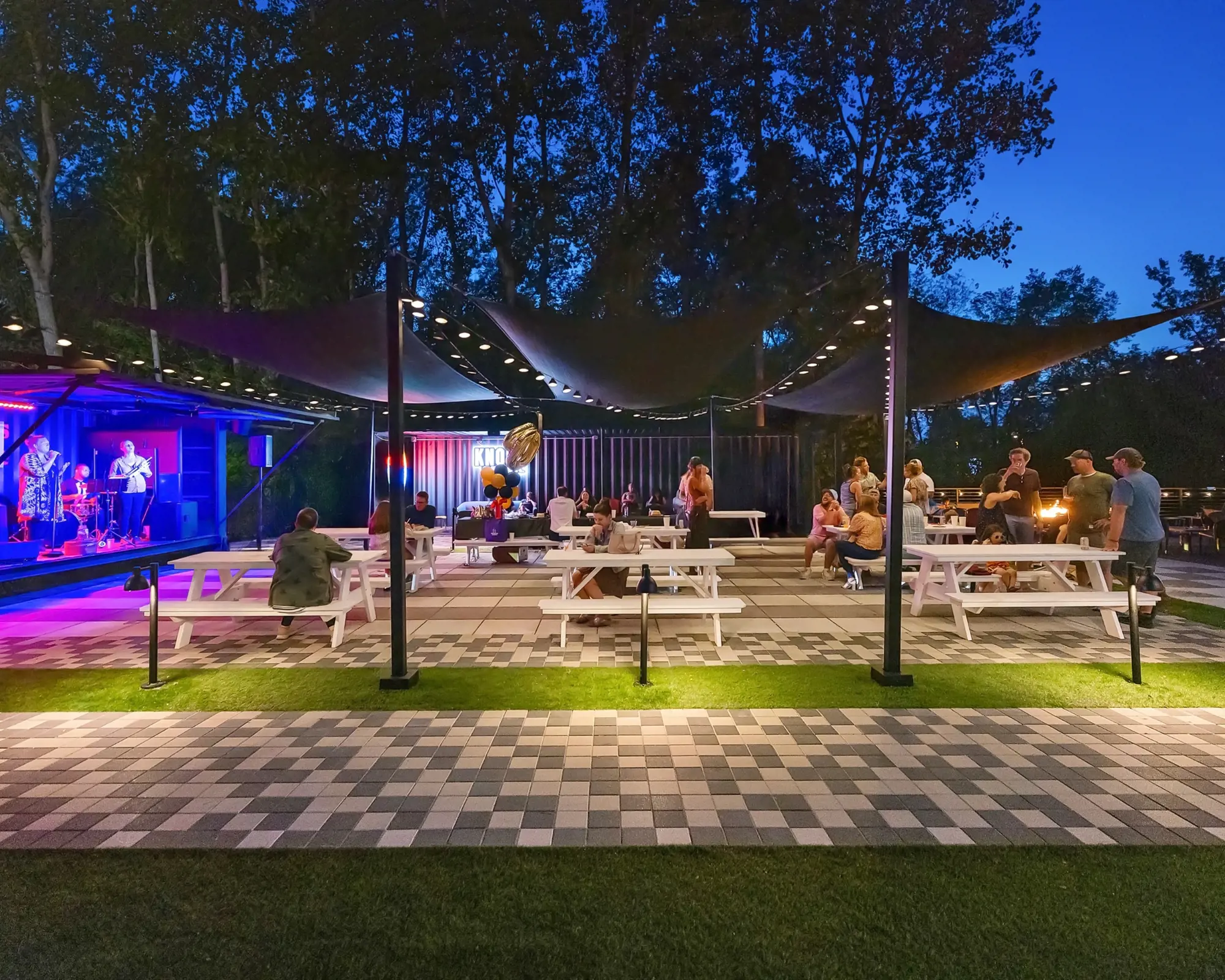 Pavés Industria 150 en disposition linéaire noir et gris au Yard at Sam Hill, encadrant la scène extérieure et l’aire de repas.