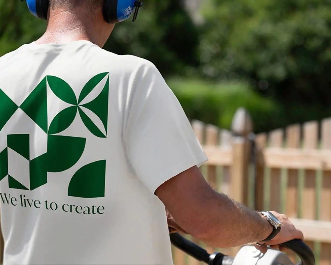 Person wearing a white Techo-Bloc co-branded T-shirt with a green logo on the back.
