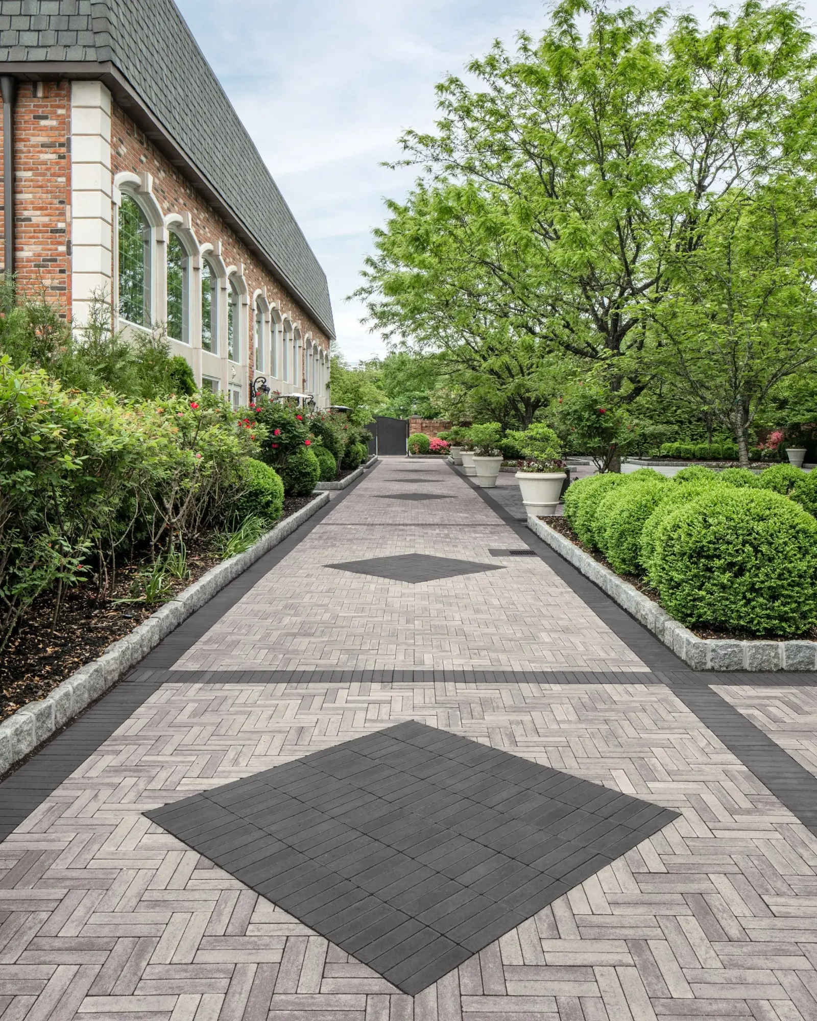 Longue allée de jardin pavée en Westmount HD² Smooth, avec dalles Gris Calcaire et accents Noir Onyx disposés en chevrons.