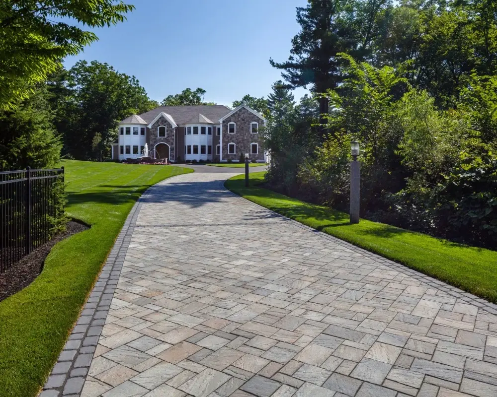 Eva Slate paver by Techo-Bloc in Champlain Grey with slate texture, used on a long estate driveway with elegant stone borders.
