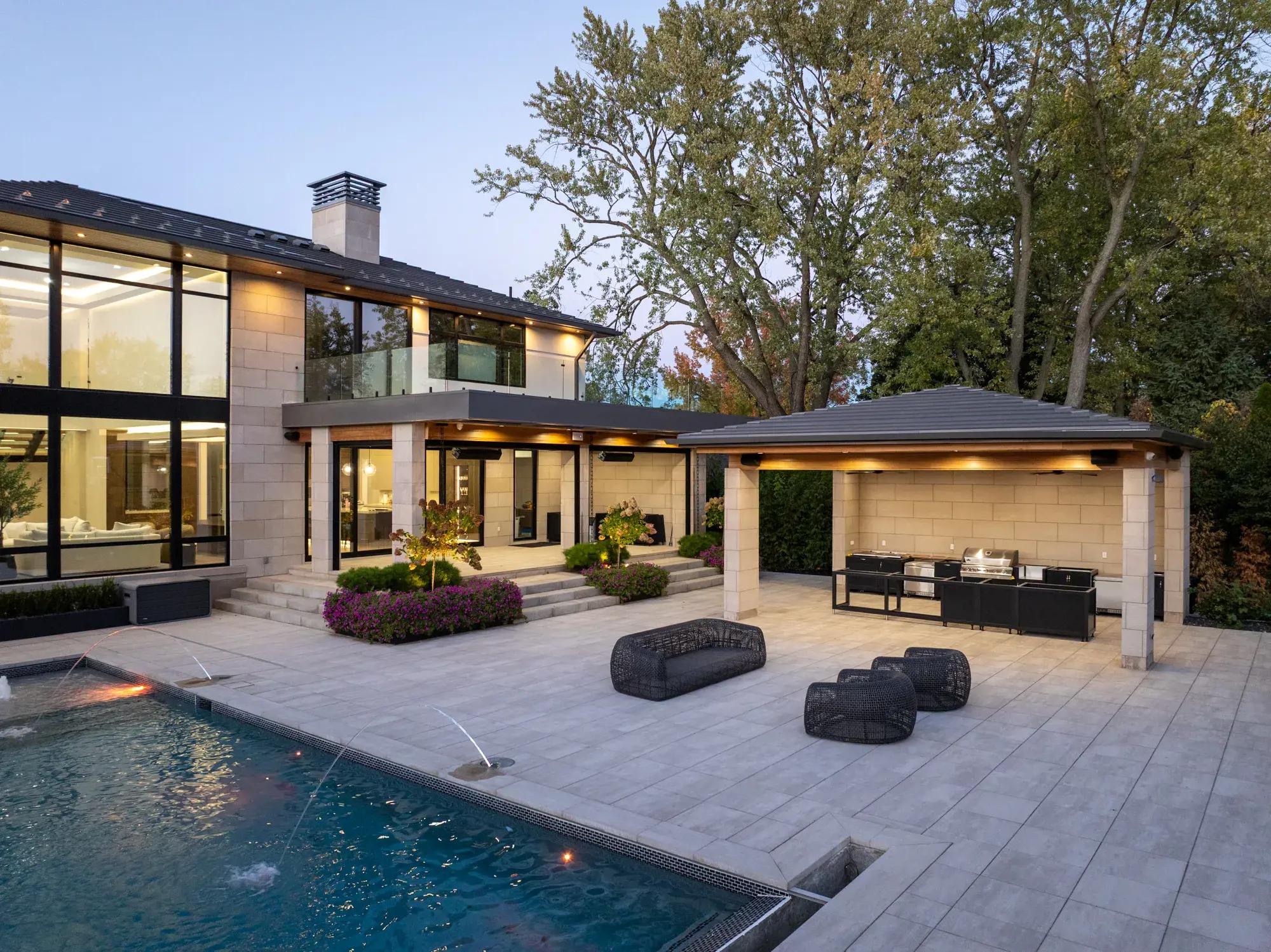 Maison moderne au crépuscule surplombant une piscine et une terrasse de piscine Industria, intérieur éclairé