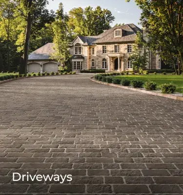 Valet pavers by Techo-Bloc in Champlain Grey with aged texture form a classic driveway leading to a large estate.