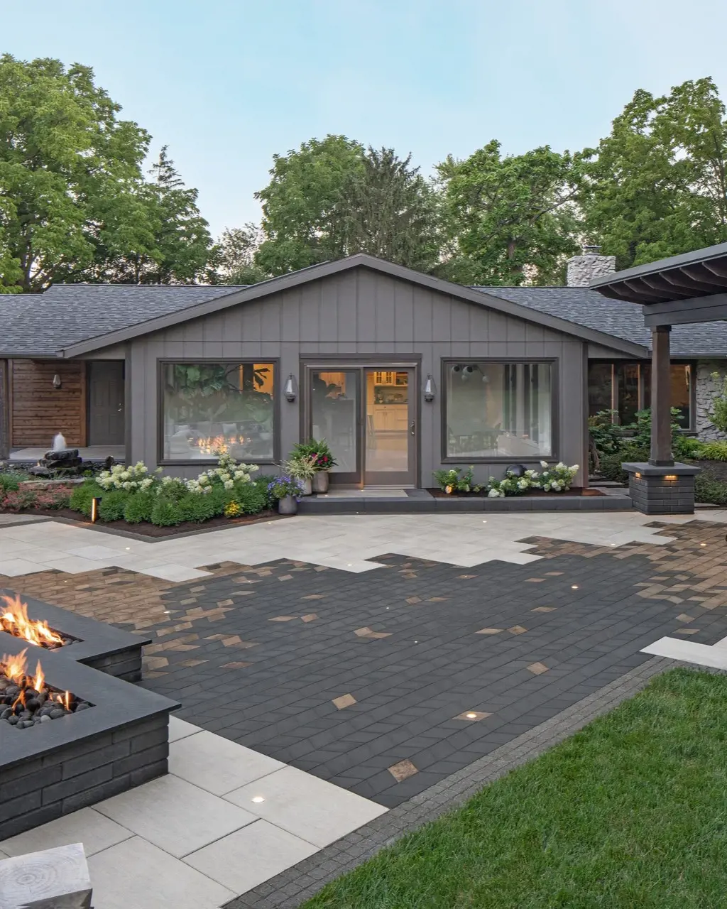 Espace extérieur avec foyer, chaises longues et pavés Techo-Bloc devant une maison moderne.