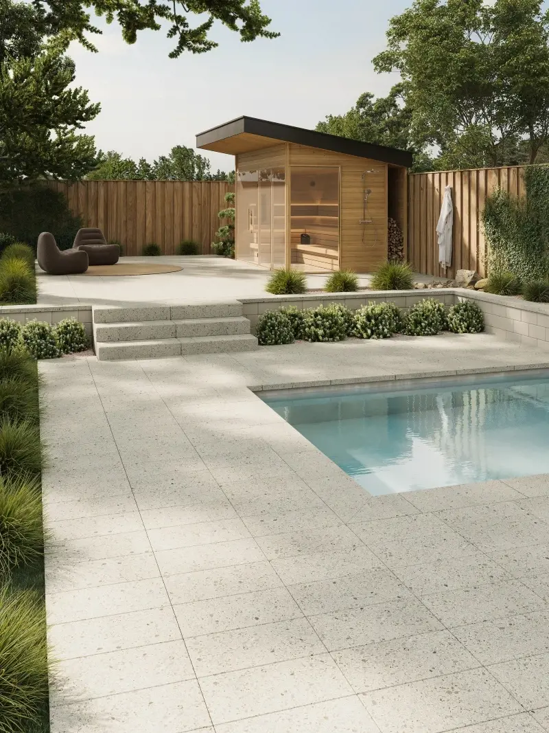 Cour arrière moderne avec pavés autour de la piscine, marches en béton, aménagement paysager et sauna en bois.