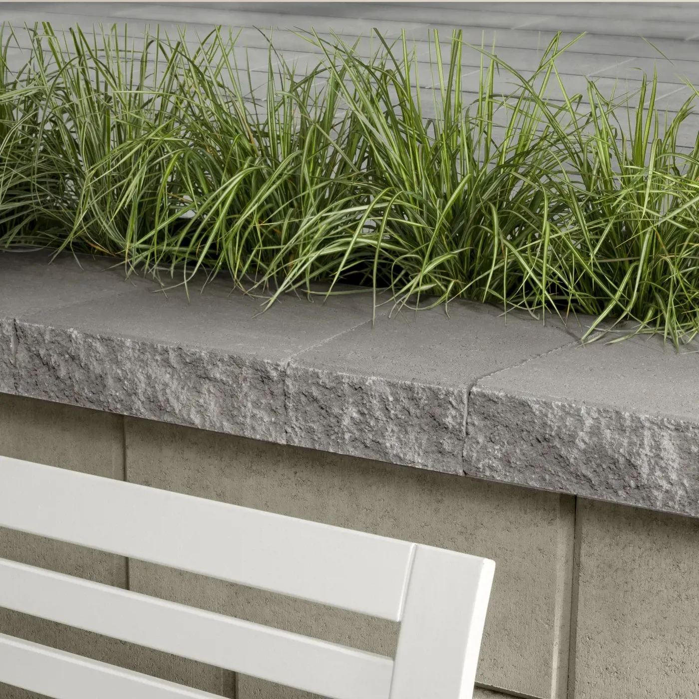 Architectural wall cap in Greyed Nickel with a smooth, modern finish, topping a contemporary retaining wall design.