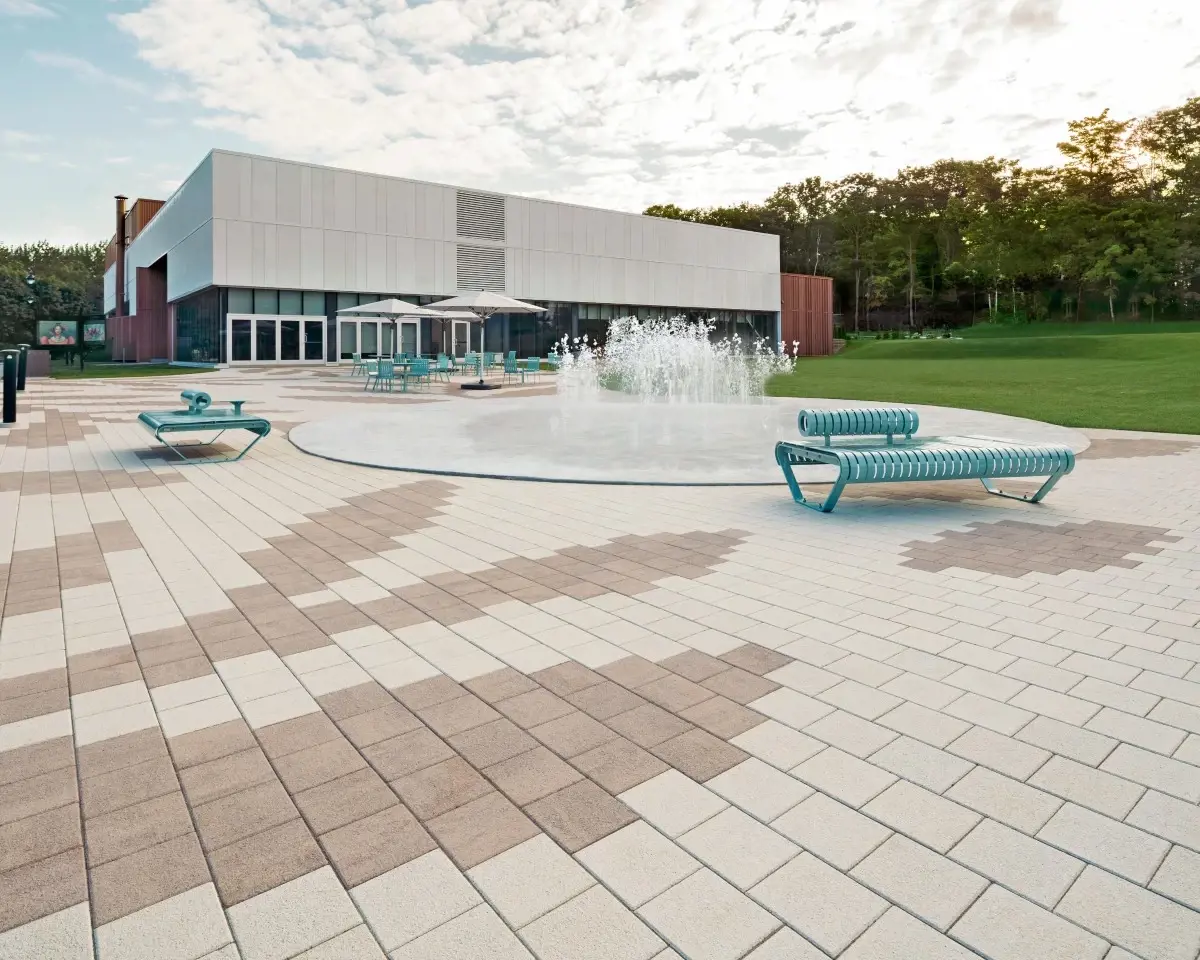 Place du centre communautaire en pavés Industria HD² Granitex de Techo-Bloc beige et brun, transformée à partir d’un ancien stationnement asphalté.