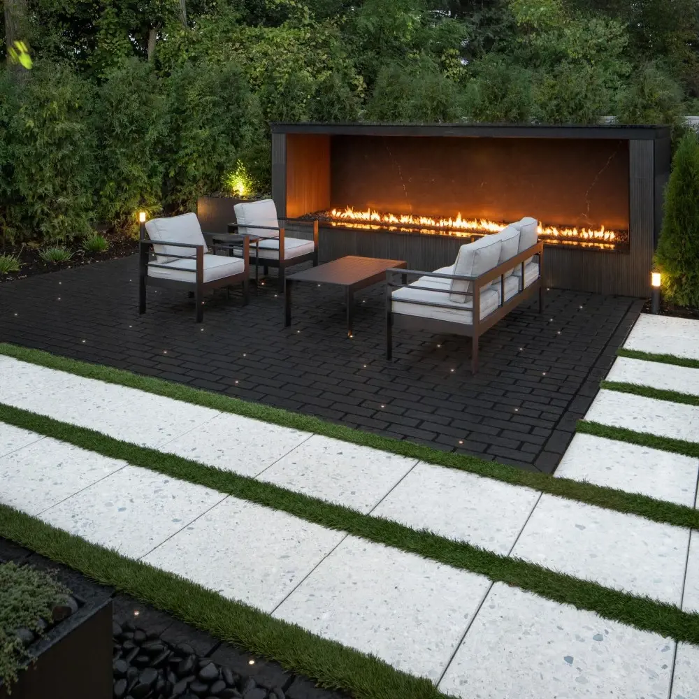 Outdoor seating area with Mika concrete pavers in Onyx Black, featuring a linear fire feature and modern lounge furniture.