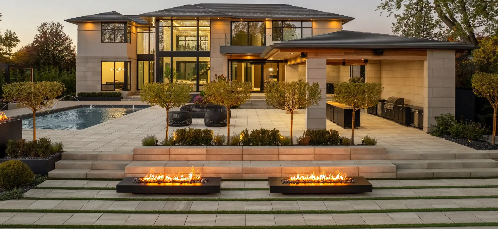 Cour arrière moderne avec des dalles de béton Industria, des marches Raffinato, des foyers intégrés et une cuisine extérieure.