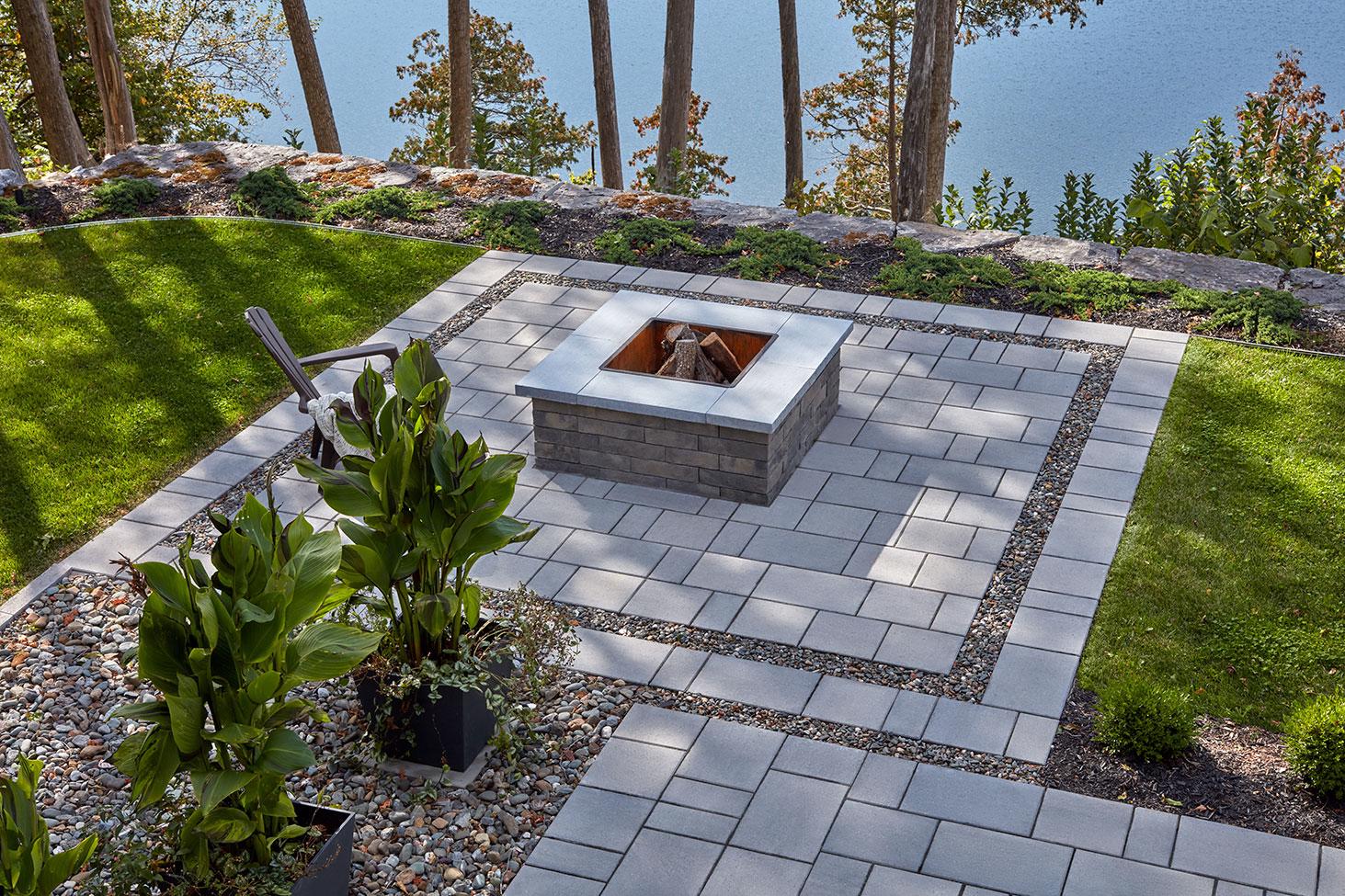Brandon Fire Pit in Shale Grey, lightly smoking in a wooded backyard patio