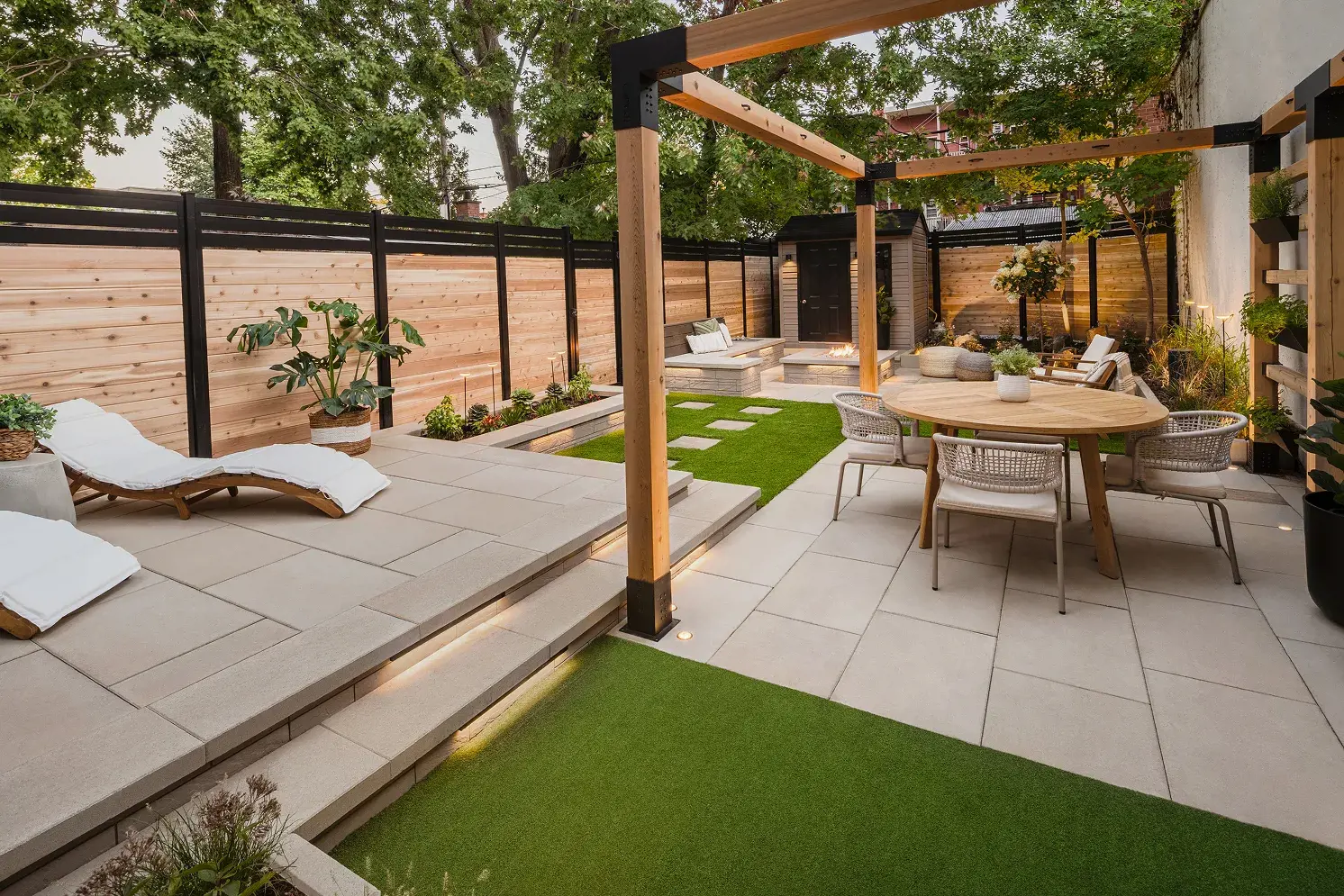 Petite cour arrière urbaine transformée en espace de vie extérieur complet avec coin repas, bande de gazon et pergola