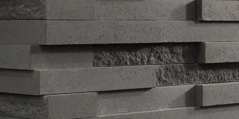 Gros plan sur le mur Graphix de Techo-Bloc, avec texture 3D dynamique et design de pierre superposée dans des tons de gris modernes.