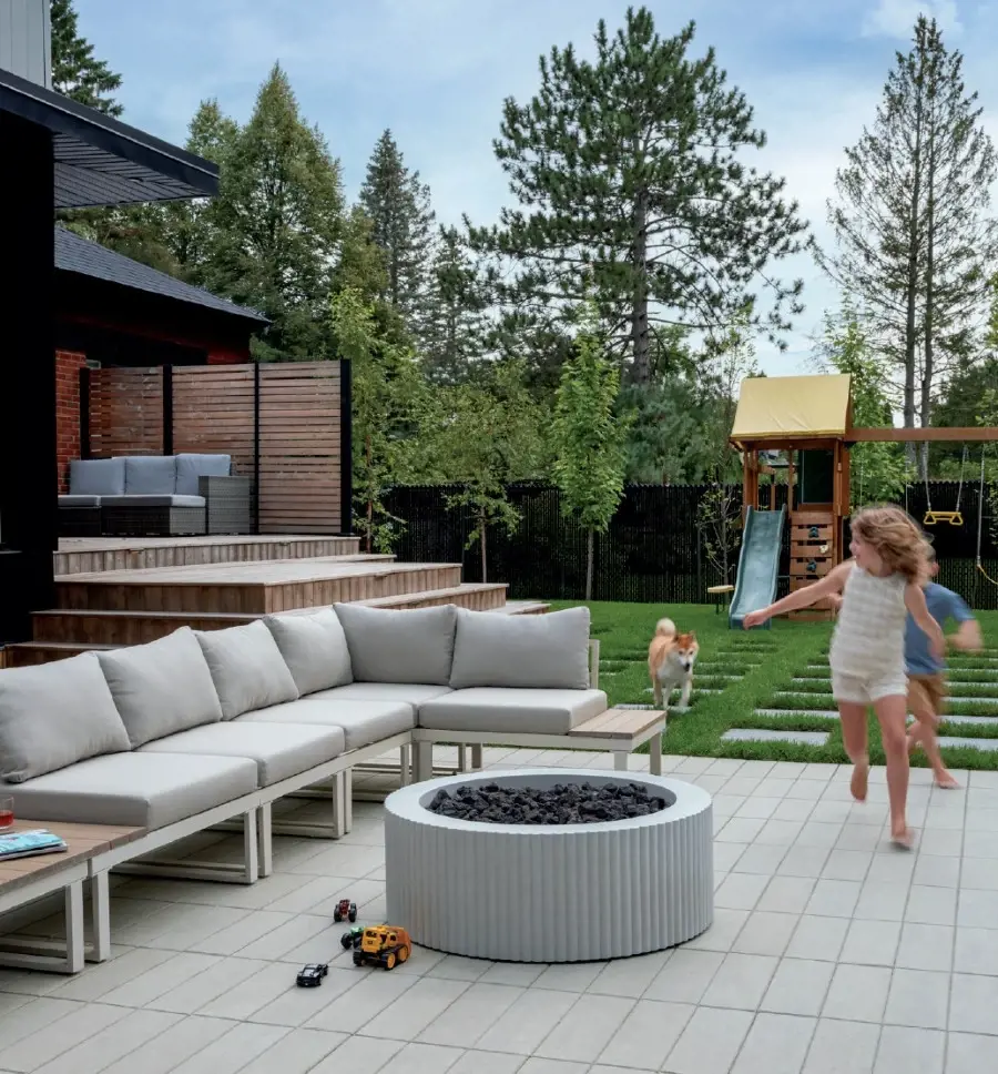 Modern backyard patio with concrete pavers, built-in fire feature, and outdoor seating.