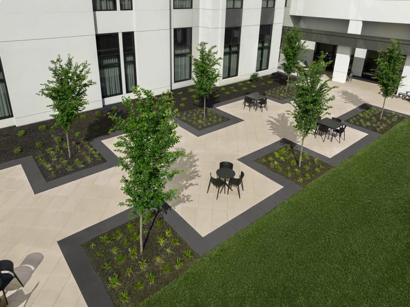 Une vue en angle de l'extérieur de l'hôtel Embassy Suites où on y voit des tables et des chaises, ainsi que les dalles commerciales Para de Techo-Bloc dans les couleurs noir onyx et beige crème.