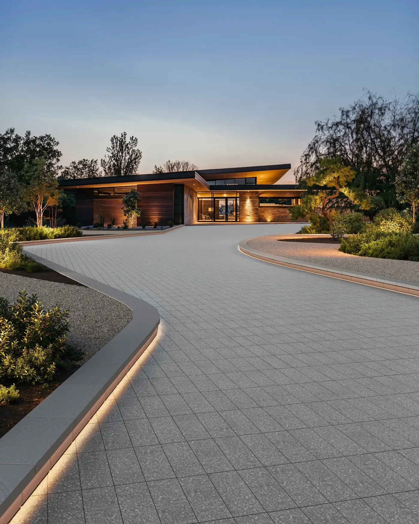 Modern residential driveway built with Techo-Bloc Terrazzo pavers in Moonrock Grey, featuring curved borders and integrated landscape lighting.