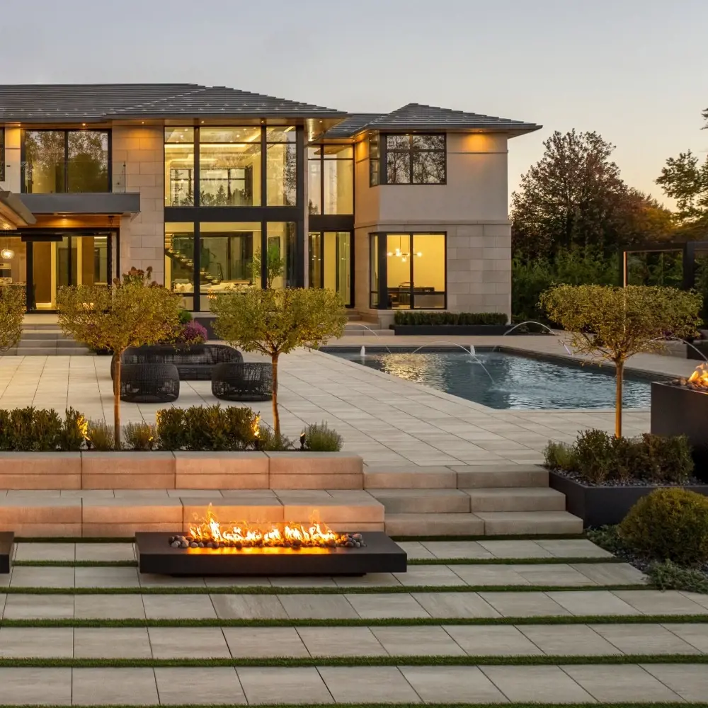 Terrasse arrière en paliers avec des marches Raffinato en béton en Caffè Crema, combinées à un pavage moderne et des foyers intégrés.