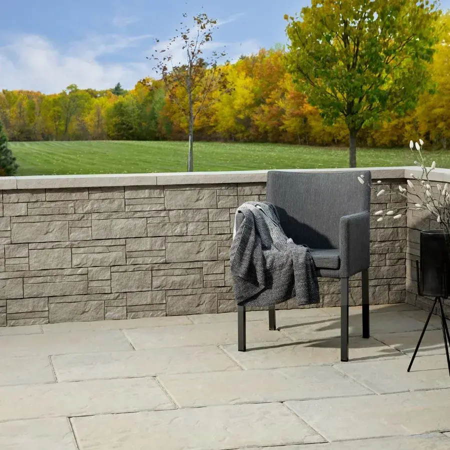 Un patio confortable avec les murs Rosemont de Techo-Bloc, présentant une texture ciselée qui apporte une ambiance naturelle et rustique à l’espace extérieur.