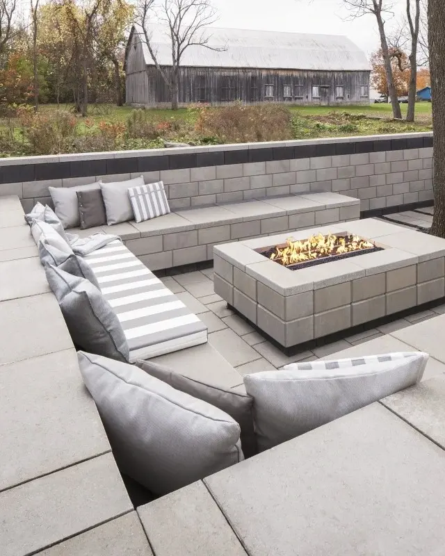 Patio encastré moderne en pierre grise avec banquettes intégrées et foyer rectangulaire pour des soirées conviviales.
