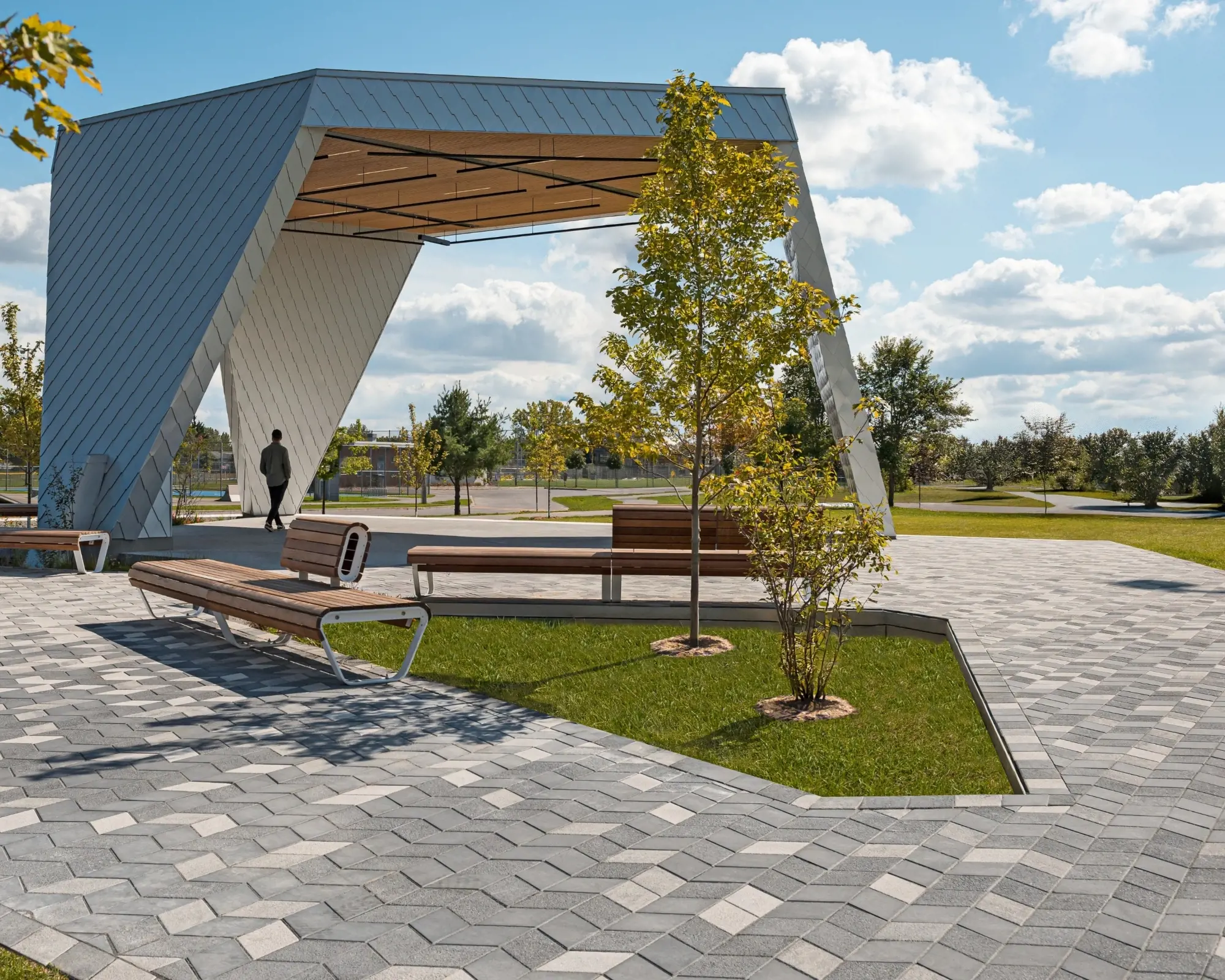 Place du parc Philippe-Villeneuve avec pavés Diamond HD² Smooth, bancs, arbres et une scène sculpturale moderne.