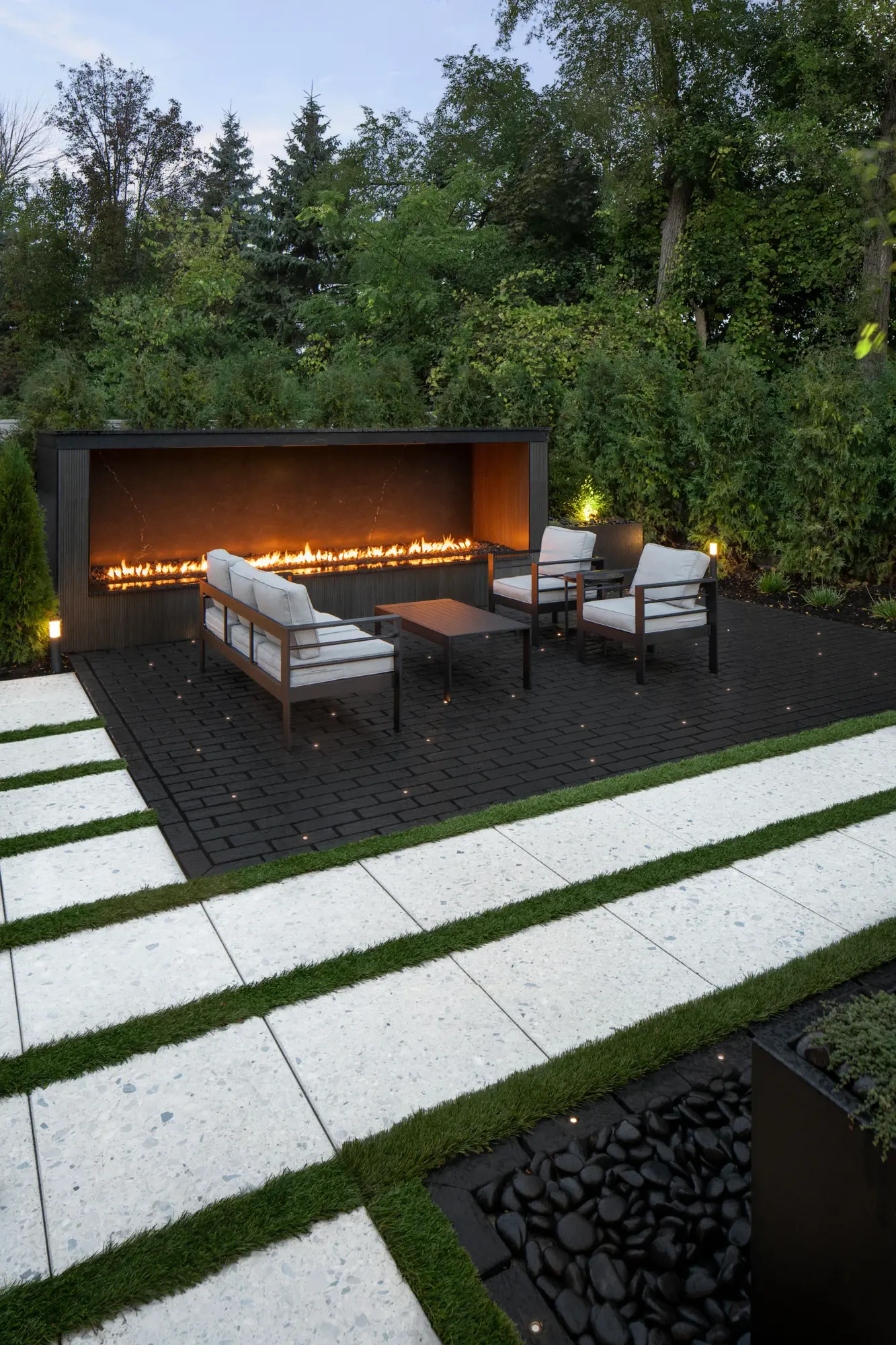 Coin salon extérieur sur pavés Mika Noir Onyx avec foyer linéaire et fauteuils
