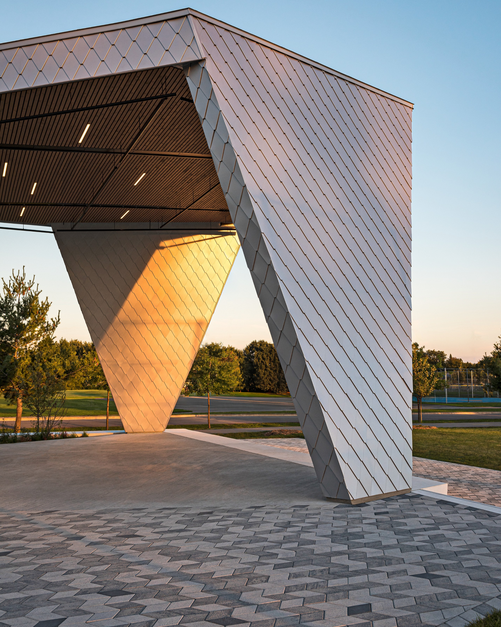 Pavés Diamond HD² Smooth en tons de gris au parc Philippe-Villeneuve sous une arche sculpturale moderne.