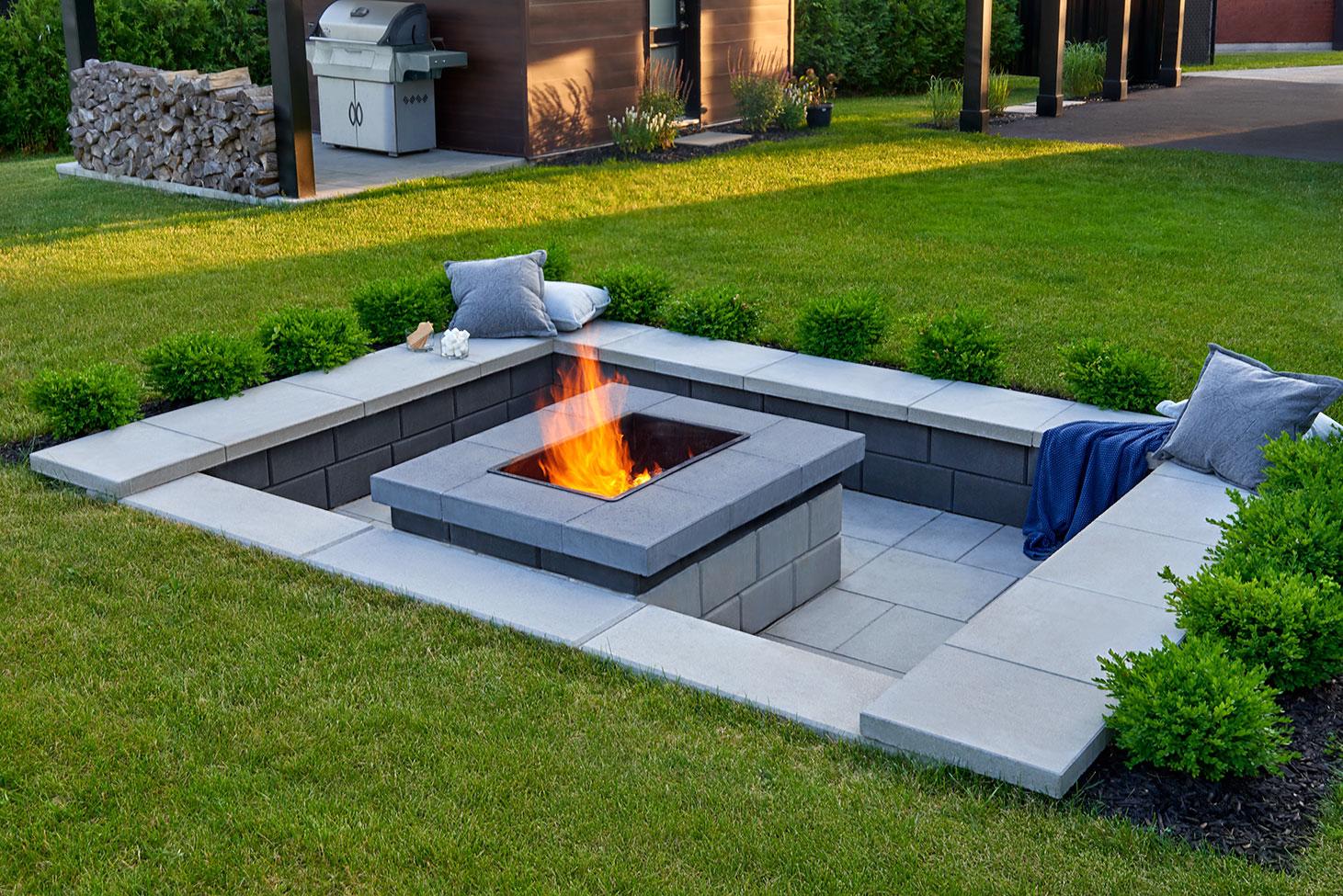 Raffinato Fire Pit in Greyed Nickel with a modern two-tone block design on a raised stone patio