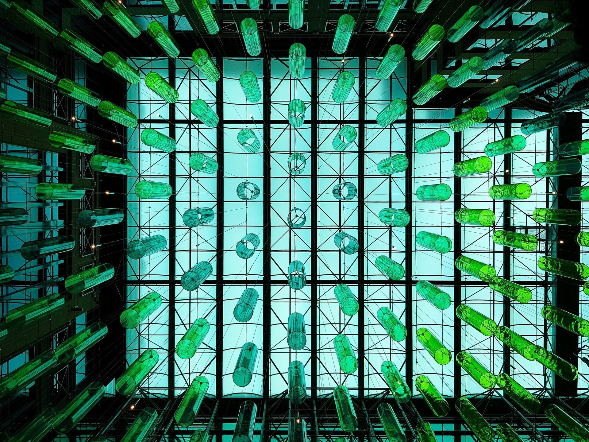 Architectural installation featuring suspended green glass elements symbolizing research into recycled materials and sustainable design