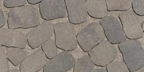 Détail des pavés Antika de Techo-Bloc, à texture de pierre naturelle et forme irrégulière, conçus pour des aménagements extérieurs rustiques et organiques.