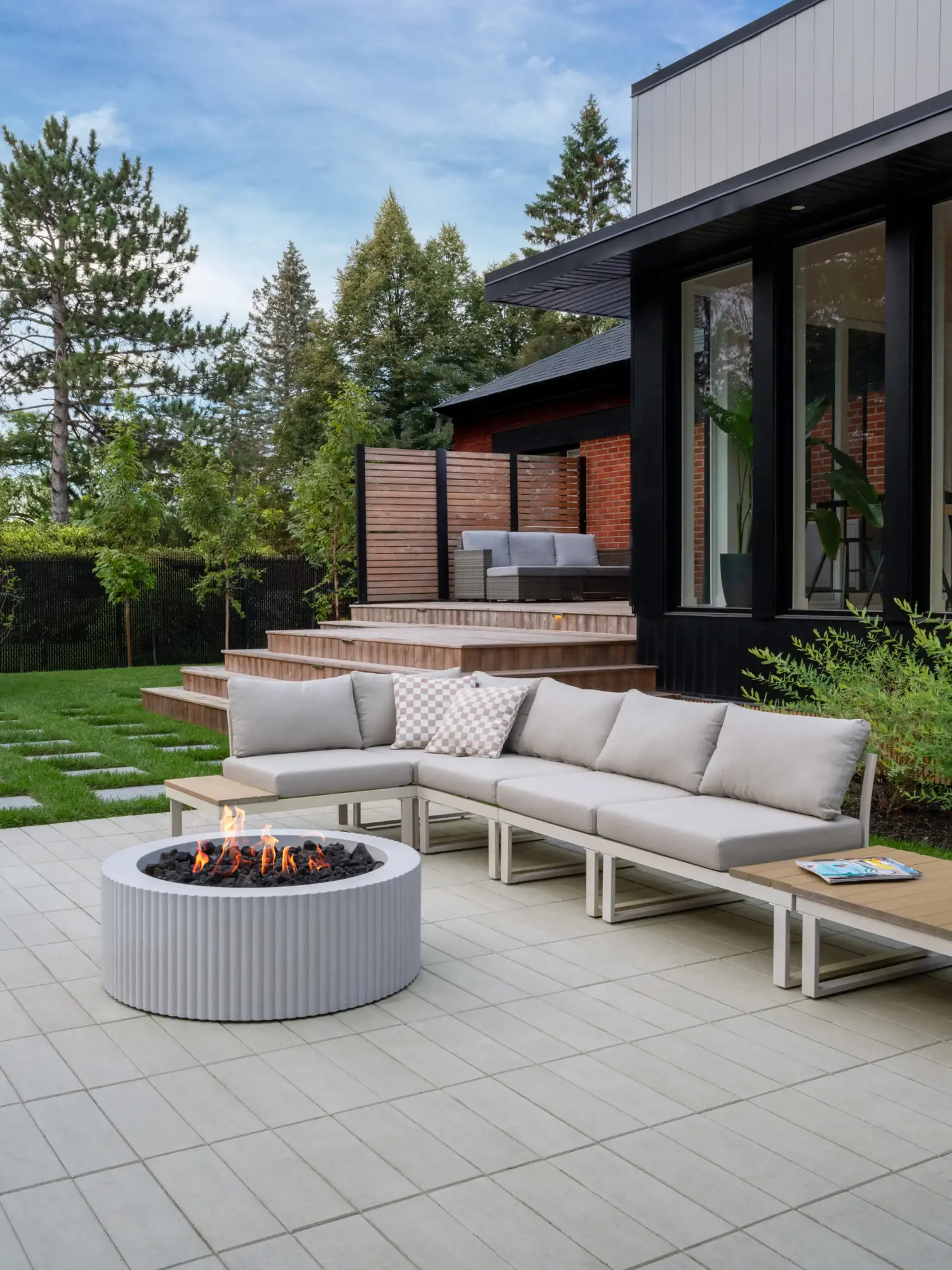 Backyard patio in large-format slabs with a fluted fire bowl and a sectional lounge