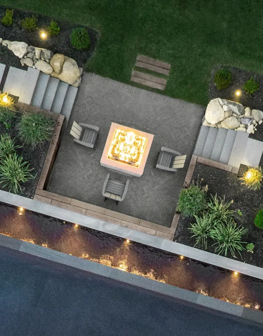 Aerial view of a modern firepit patio featuring Techo-Bloc Westmount Pavers in Onyx Black arranged in a herringbone pattern.