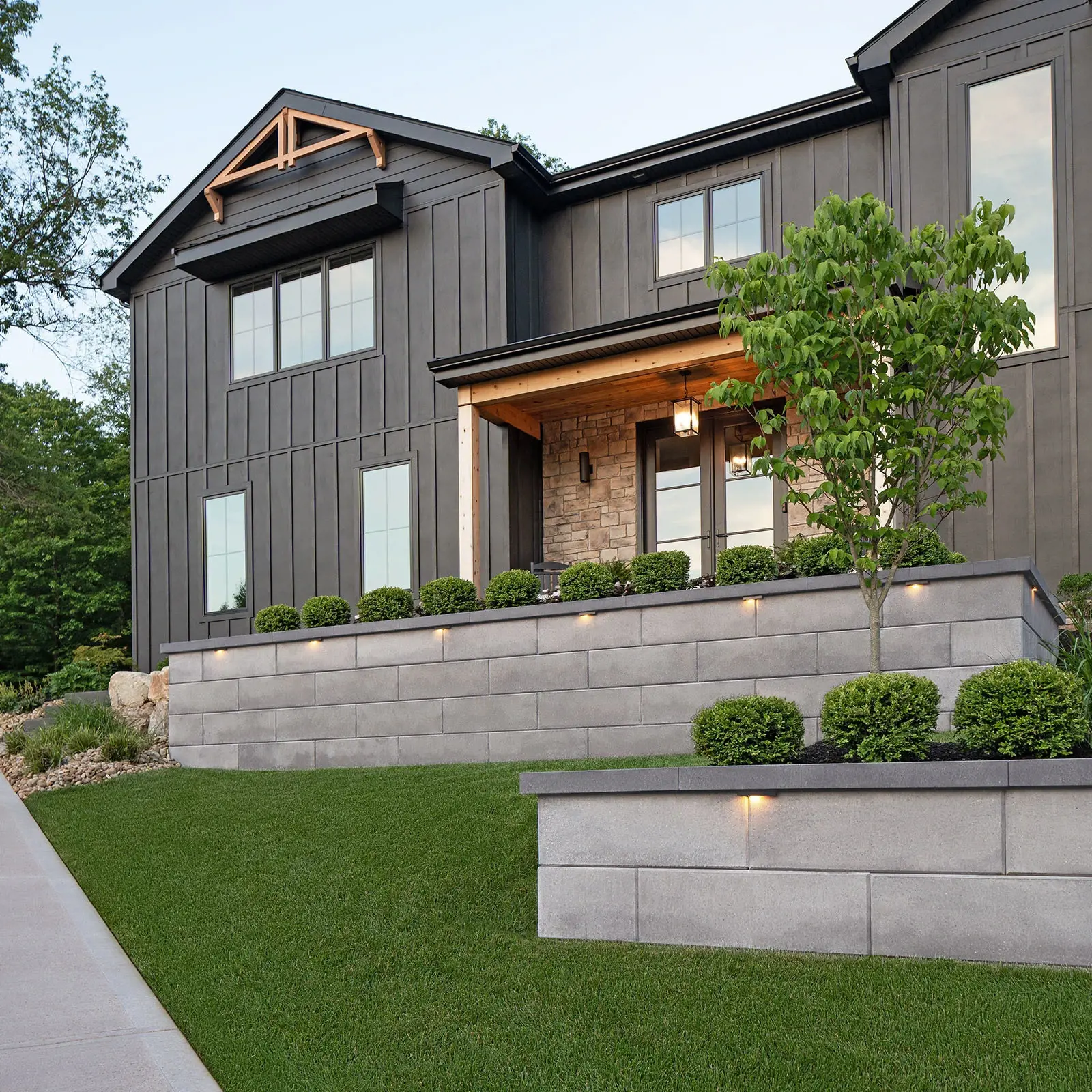 Skyscraper Wall in Shale Grey building tiered front yard walls with dark caps and accent lighting