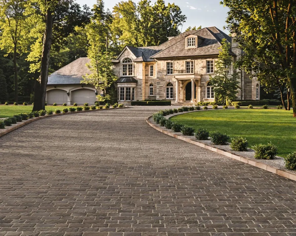 Entrée courbée menant à une maison de style classique, aménagée avec le pavé Oxford de Techo-Bloc au fini pierre vieillie—idéal pour les maisons au style intemporel.