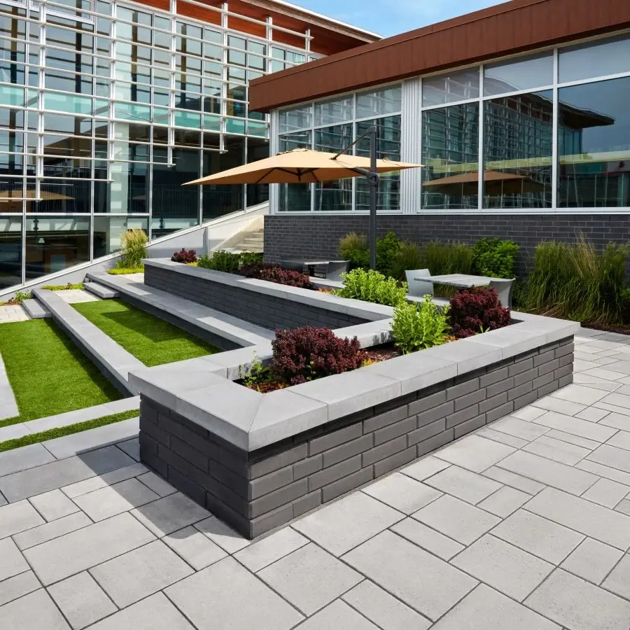 Espace extérieur de campus éducatif avec des jardinières modernes en murs Raffinato et pavés Blu 80 Smooth de Techo-Bloc pour un design contemporain et épuré.