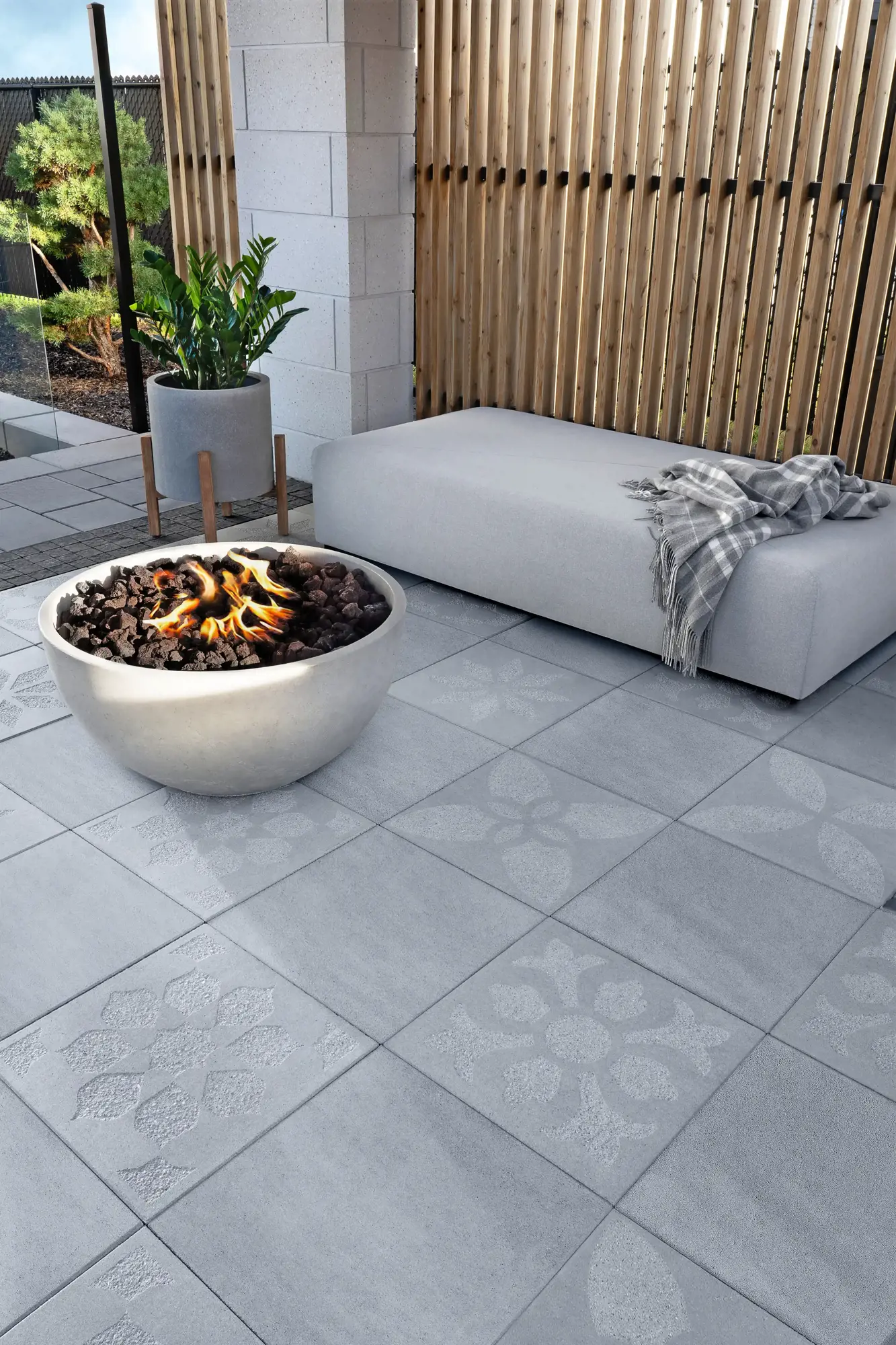 Sculptura Lumi Firebowl, a round concrete bowl filled with lava stones and flickering flames