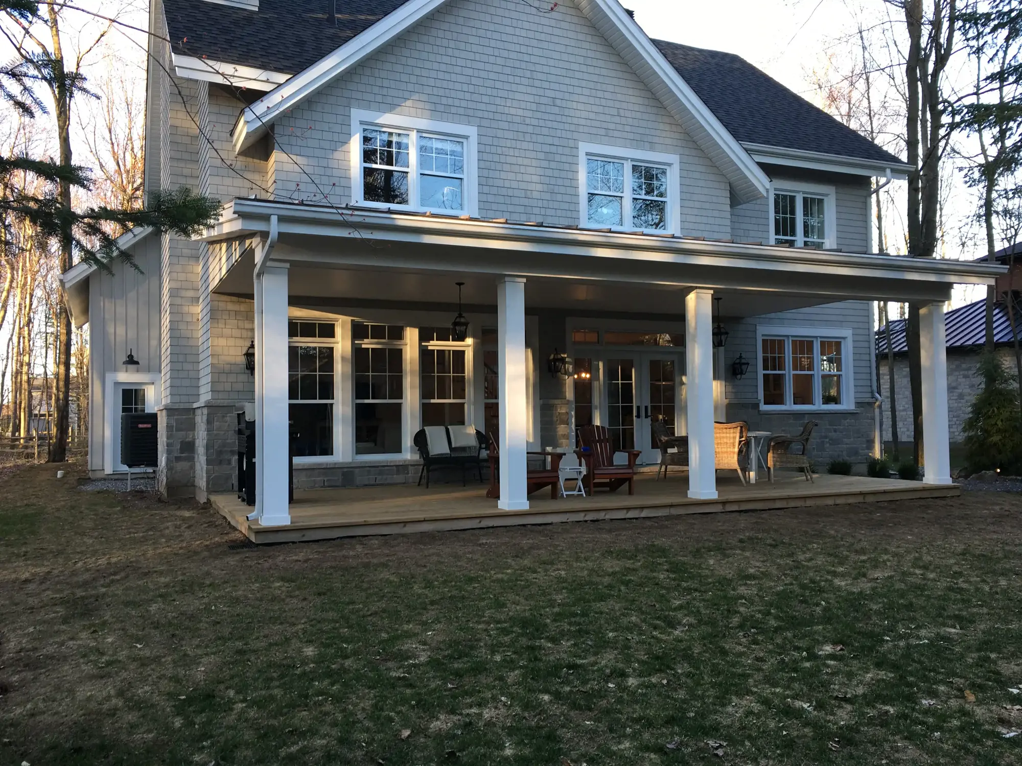 Extérieur de la maison avec terrasse couverte et pelouse dégarnie avant la rénovation de la cour